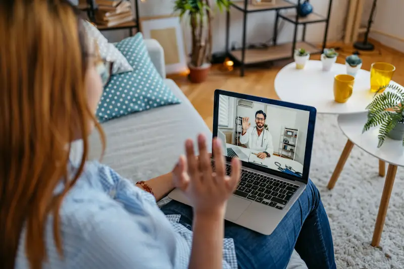 Paciente realizando consulta virtual online desde computador para atención médica a distancia con profesional certificado